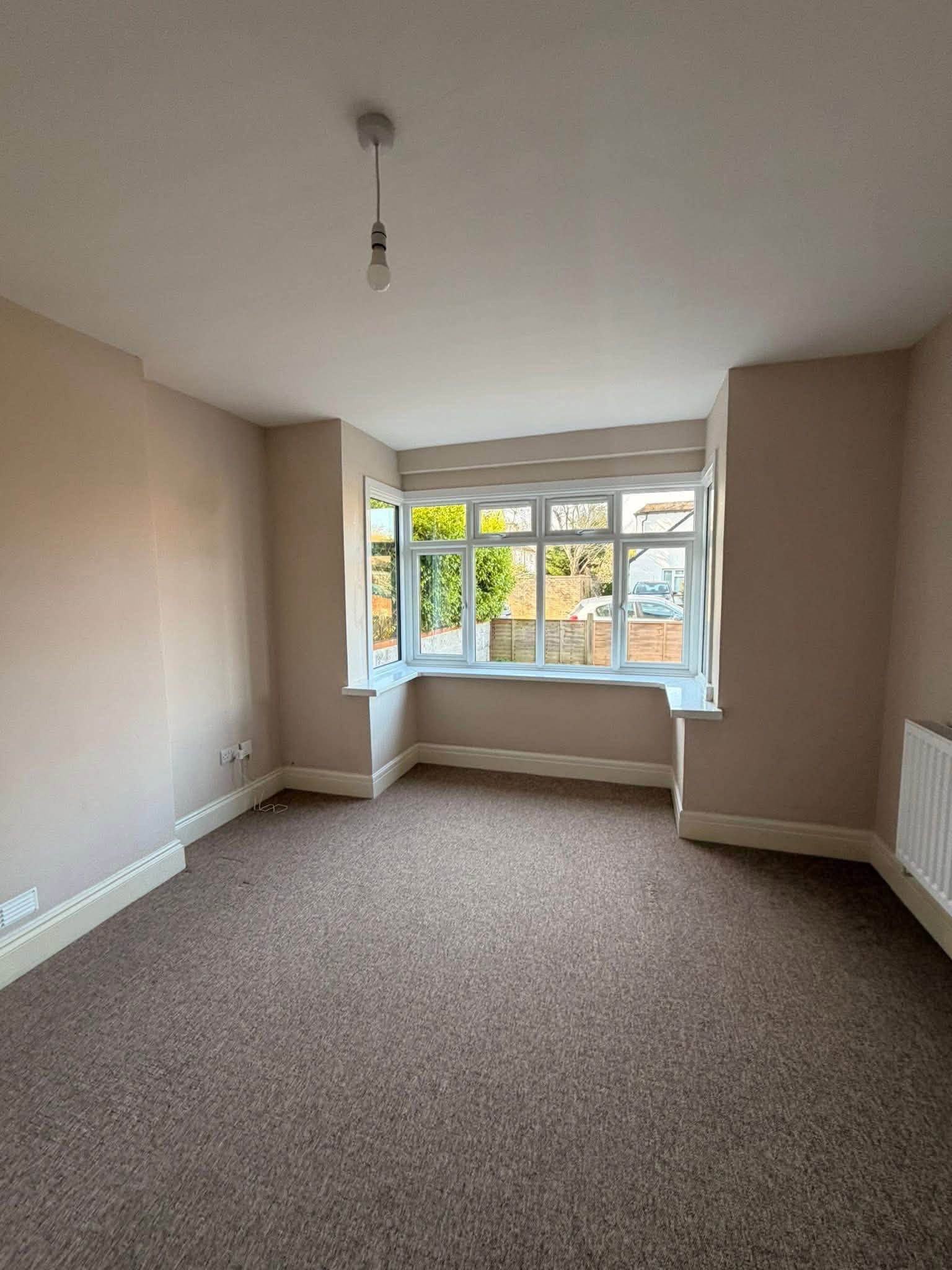 A bright, freshly cleaned living room with a spotless carpet and clear bay window